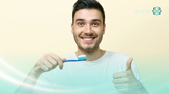 صورة-توضح-رجل-يبتسم-بثقة-و-يحمل-فرشاة-أسنان-عليها-معجون-مع-علامة-ممتاز-بيده-الأخرى-مما-يوضح-أهمية-اختيار-أفضل-معجون-أسنان-لروتينك-اليومي صورة-توضح-رجل-يبتسم-بثقة-و-يحمل-فرشاة-أسنان-عليها-معجون-مع-علامة-ممتاز-بيده-الأخرى-مما-يوضح-أهمية-اختيار-أفضل-معجون-أسنان-لروتينك-اليومي.